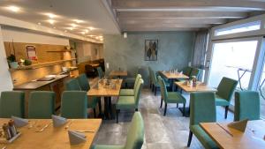 une salle à manger avec des tables en bois et des chaises vertes dans l'établissement Vico's Hotel & Restaurant Asperg, à Asperg