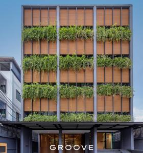 un bâtiment avec des plantes sur son côté dans l'établissement GROOVE AT SIAM, à Pom Prap