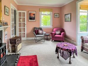 uma sala de estar com paredes cor-de-rosa, 2 cadeiras e uma mesa em Glen Mhor em Glenelg