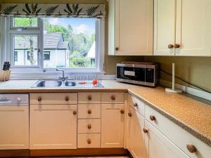 a kitchen with a sink and a microwave and a window at Glen Mhor in Glenelg