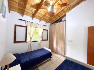 1 dormitorio con 1 cama azul y ventilador de techo en La Casita de Karen en Villa General Belgrano