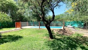 a tree in a yard next to a fence at La Casita de Karen in Villa General Belgrano