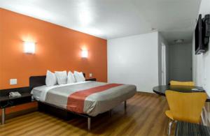 um quarto com uma cama com uma parede laranja em Beachside Inn em Anaheim