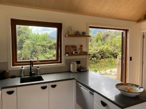 a kitchen with a sink and a large window at Uru Ecohomes in Seddonville