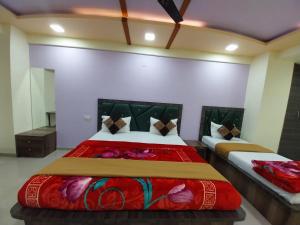 1 dormitorio con 2 camas y mantas rojas en Hotel GGC INN en Ahmedabad