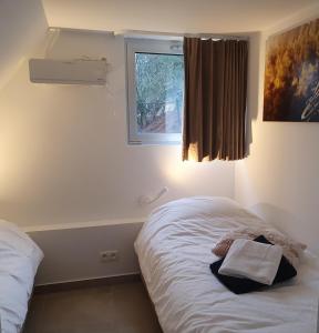 a small bedroom with a bed with a window at Aux 4 vents - Malmedy in Malmedy