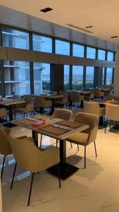 uma sala de jantar com mesas, cadeiras e janelas em Al Rayyan Tower em Jeddah