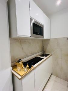 a white kitchen with a sink and a microwave at Suite del Ponte in Varese