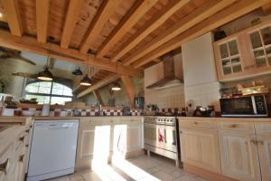 eine große Küche mit weißen Geräten und Holzdecken in der Unterkunft Gite de groupe "L'Unisson" Domaine La Rose des Vents in Castelnau-sur-lʼAuvignon