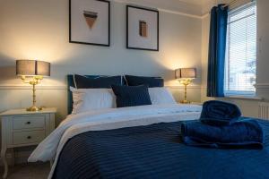 Kent的住宿－Stunning 2 Bed House-Long Stay Offer-Parking，一间卧室配有一张带蓝色毯子和两盏灯的床。