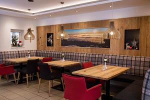 a restaurant with wooden tables and red chairs at Landhotel Eibl in Röhrnbach