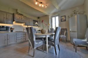 eine Küche mit einem Tisch und Stühlen sowie einem Kühlschrank in der Unterkunft Gîte Le Bon Sens - Domaine la Rose des vents in Castelnau-sur-lʼAuvignon