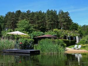 a table with an umbrella and chairs on a dock in the water at Ferienhaus SEERESIDENZ am Mühlensee in Godern