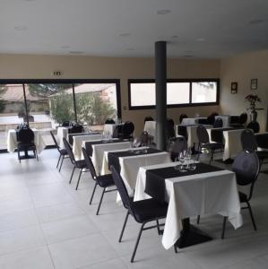 un comedor con mesas y sillas blancas en Hôtel Restaurant Mas del Gall, en Castelnou