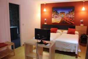 a bedroom with a bed and a desk with a computer monitor at Hostal Falfes in Madrid