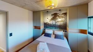 un pequeño dormitorio con una cama y una pintura en la pared en Villa Ananda - Gâia - Harmonie avec vue mer et étangs, en Carnon-Plage