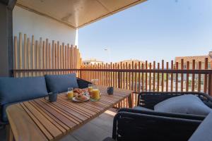 d'un balcon avec une table en bois et deux chaises. dans l'établissement Villa Ananda - Gâia - Harmonie avec vue mer et étangs, à Carnon-Plage