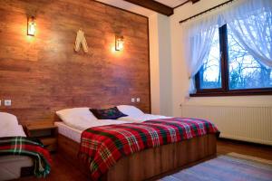 1 dormitorio con 1 cama y pared de madera en Къщи за гости НЕСИ en Leshten