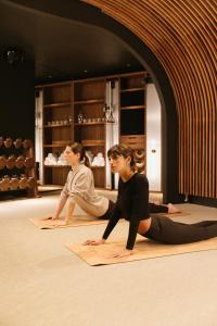 Due donne sedute sul pavimento in una lezione di yoga di Hôtel Dame des Arts a Parigi