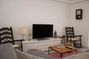 a living room with a flat screen tv and chairs at Apartamento Catòlics 25 in Pollença