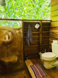 a bathroom with a toilet in a room with trees at Casonita in Manzanillo