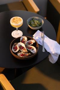 a table with a plate of oysters and a drink at Hôtel Dame des Arts in Paris