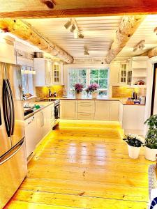 a large kitchen with wooden floors and white cabinets at Timber house with private beach and boat including. in Njurundabommen