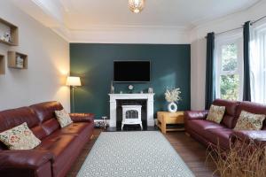a living room with two leather couches and a fireplace at Kenmare Cottage in Shanklin
