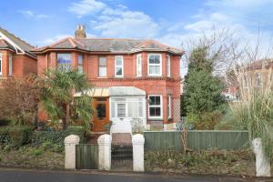 a red brick house with a fence in front of it at Kenmare Cottage in Shanklin