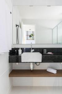 La salle de bains blanche est pourvue d'un lavabo et d'un miroir. dans l'établissement Apartamento Lindo e Completo - Wai Wai Cumbuco, à Cumbuco