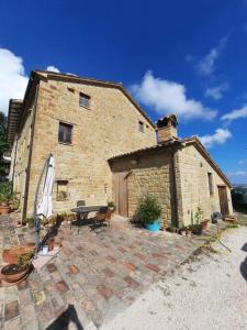 - un bâtiment en briques avec une table et un parasol dans l'établissement Country House Marche Nascoste, à San Girolamo di Sopra
