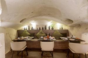 jadalnia ze stołem i białymi krzesłami w obiekcie Le Malve Cave Retreat w mieście Matera