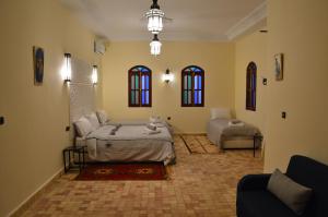 a room with two beds and a couch and windows at Le Domaine M in Ouzoud
