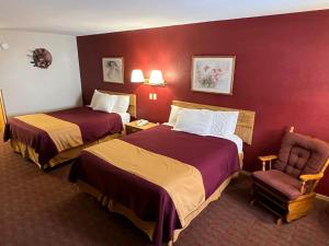 a hotel room with two beds and a chair at Americas Best Value Inn Suburban in Emmetsburg