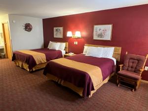 a hotel room with two beds and a chair at Americas Best Value Inn Suburban in Emmetsburg
