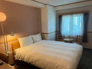 um quarto de hotel com uma cama, uma mesa e um candeeiro em Toyoko Inn Busan Seomyeon em Busan