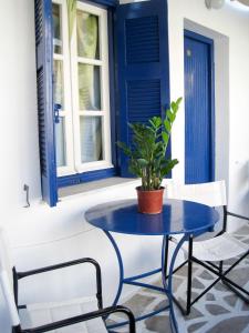 une table bleue et des chaises sur une terrasse couverte avec une plante dans l'établissement Drakos Twins, à Mylopotas