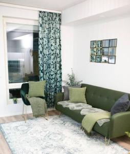 a living room with a green couch and two chairs at New studio apartment with free parking in Kuopio