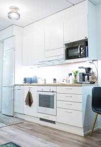 a kitchen with white cabinets and a microwave at New studio apartment with free parking in Kuopio