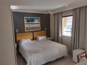 1 dormitorio con cama blanca y ventana en Lemes Hotel, en Barra do Piraí