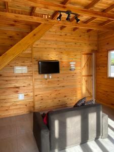 sala de estar con sofá y TV en la pared en Cabana dos Pinheiros Chalé com Jacuzzi, en Florianópolis