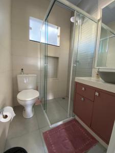 a bathroom with a toilet and a glass shower at Mini Casa na praia! in Bombinhas