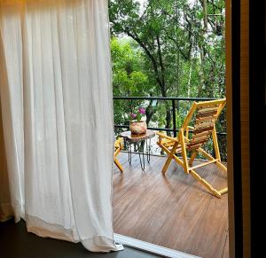 a balcony with a chair and a table and a window at Botánica Iguazú The House Experience in Puerto Iguazú