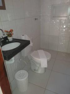 a white bathroom with a toilet and a sink at Chalés Caiçara Praia de Ponta Grossa in Icapuí