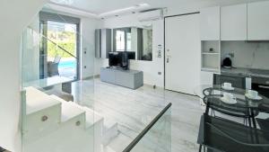 a white kitchen with a glass table and a television at Villa Marietta The First in Hanioti