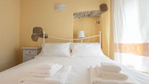 una camera da letto con un letto e asciugamani bianchi di Sardinian Gallery Fonte a Bosa