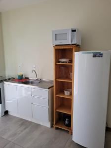 uma cozinha com um frigorífico branco e um micro-ondas em Morada da Figueira em Bombinhas