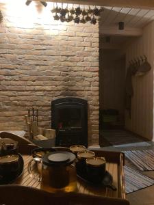 a table with pots and pans in front of a fireplace at Lauku māja Akmeņkalni in Daugmale