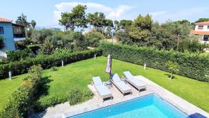 Un patio trasero con piscina y dos tumbonas y una sombrilla. en Villa Marietta The First, en Chaniotis