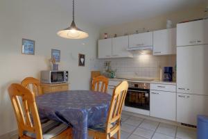 a kitchen with a table and chairs and a kitchen with white cabinets at DW10a FeWo Diekkieker in Spieka-Neufeld